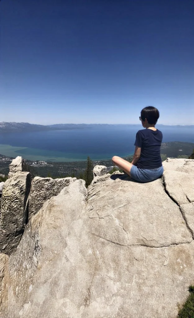 Debora Roca life coach and owner of wellness from within sitting on a mountain.