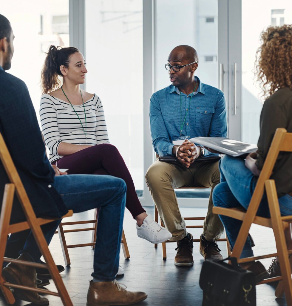 Group mental health workshop participants sitting in a circle sharing.
